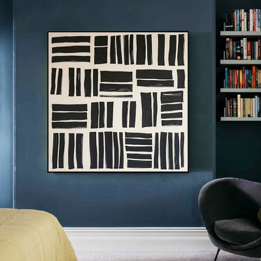 Abstract black and white artwork on a blue wall with a bookshelf in the background.