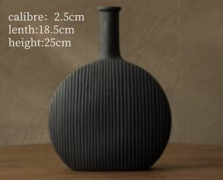 Black ribbed vase on a wooden surface with measurements displayed.