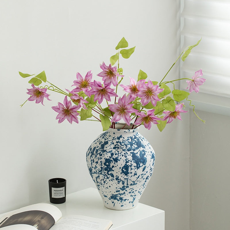 Blue and white speckled vase with pink flowers on a white surface