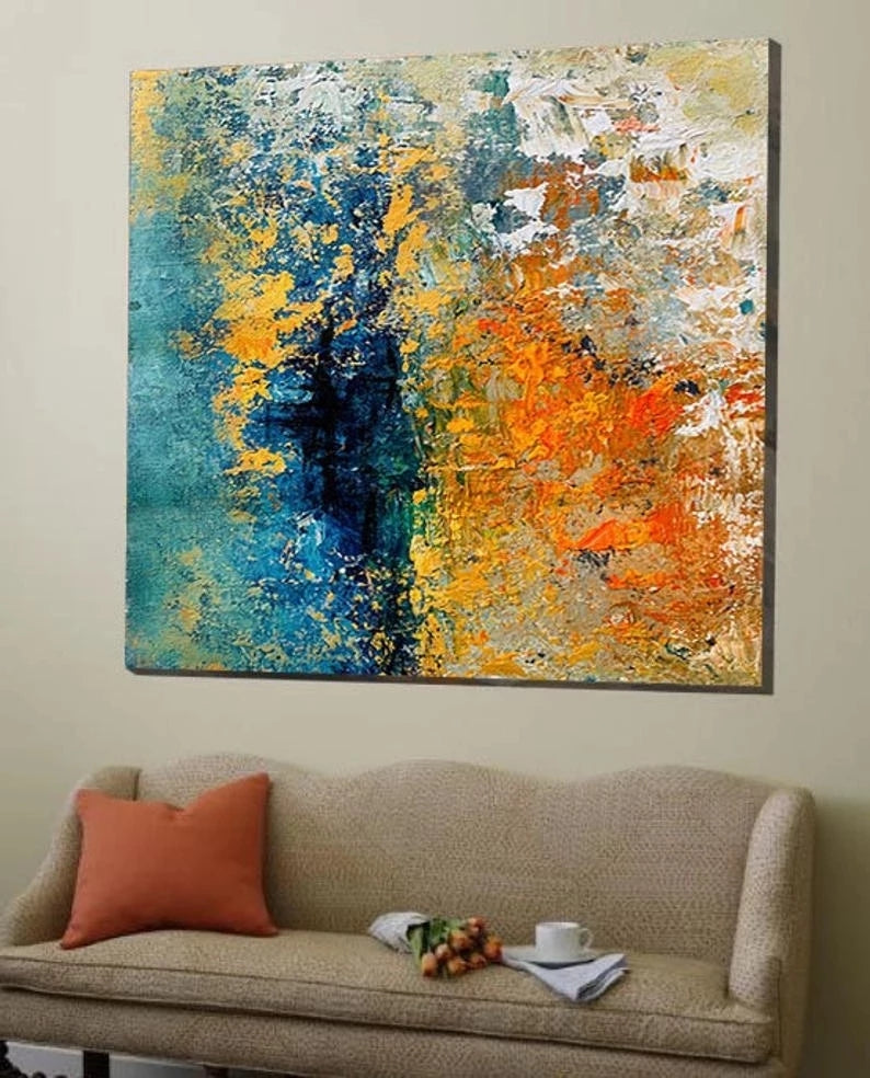 Abstract painting with blue, orange, and yellow colors on a wall above a beige sofa.