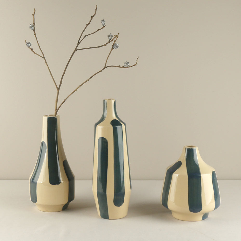 Three ceramic vases with green and beige design on a neutral background