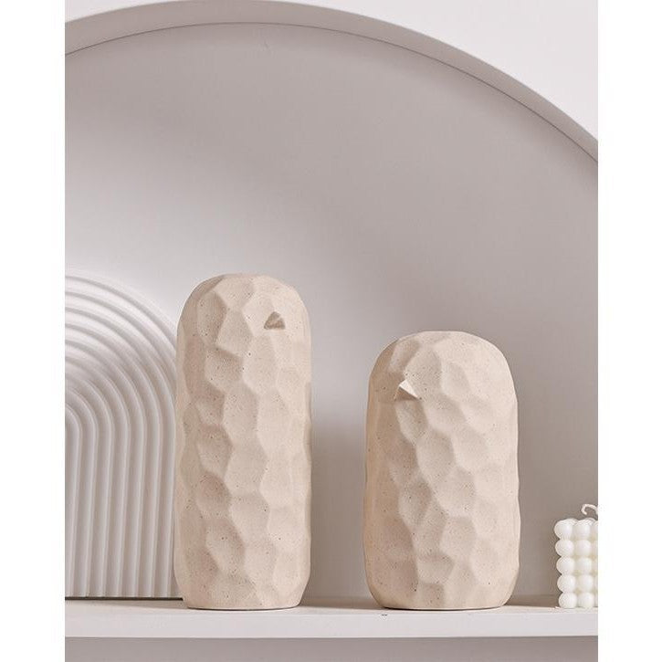 Two beige ceramic vases on a white shelf with a neutral wall background