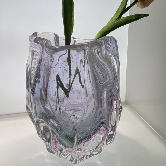 Glass vase with marbled design holding a plant on a white surface