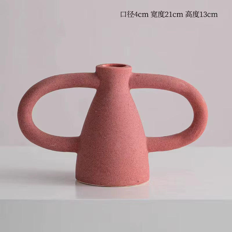 Pink ceramic vase with two handles on a light gray background