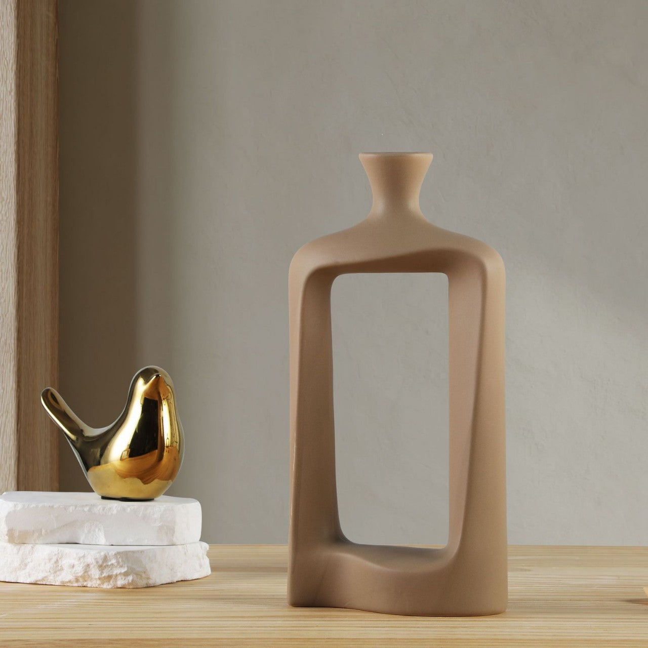 Decorative vase and gold bird sculpture on a wooden surface with a neutral background