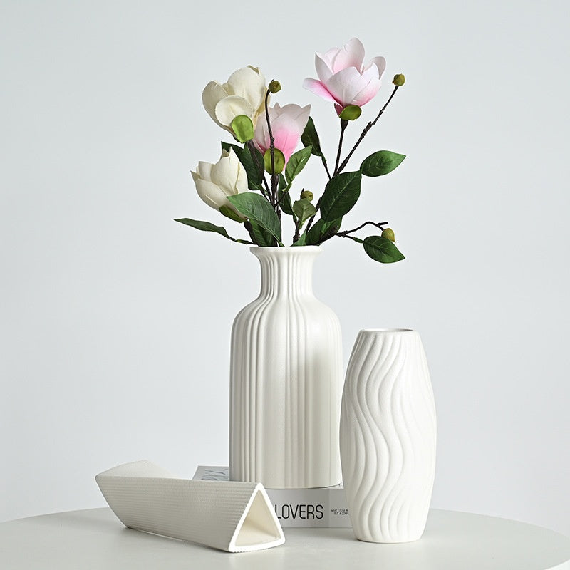 White ceramic vase with floral arrangement on a light gray background