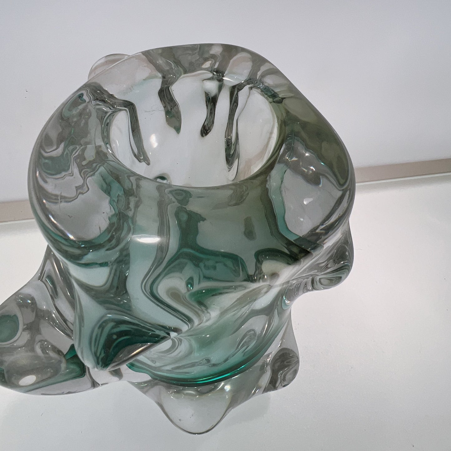 Glass sculpture with green and clear patterns on a white background
