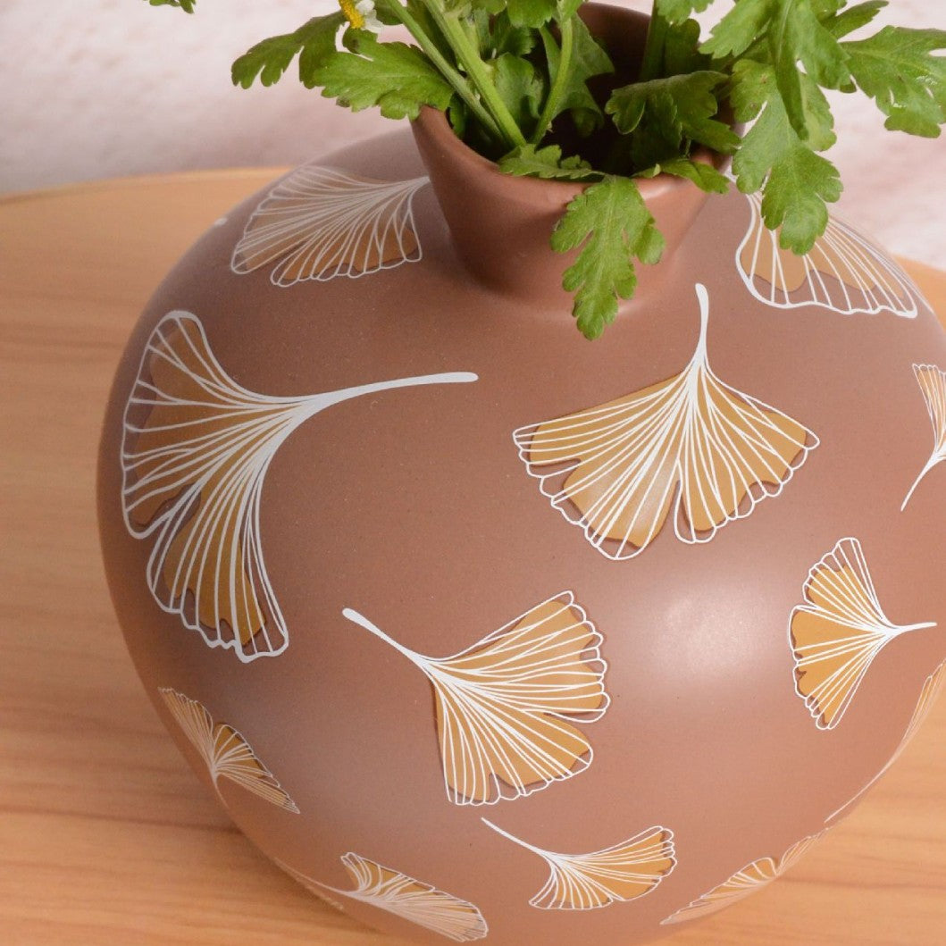 Ceramic vase with leaf pattern on a wooden surface
