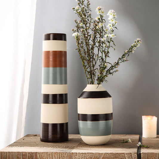 Two decorative vases with striped patterns on a wooden surface against a gray wall.