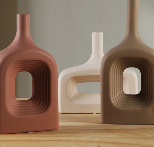 Three ceramic vases with unique designs on a wooden surface.