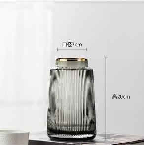 Glass vase with ribbed design and gold rim on a white background