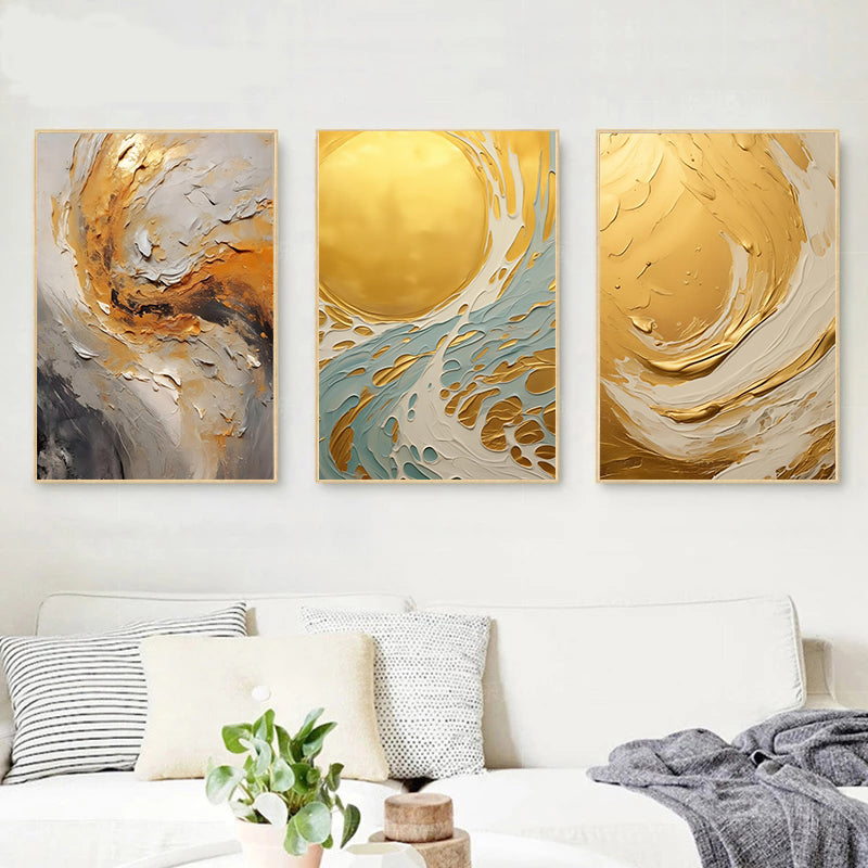 Three abstract art pieces in gold, gray, and white on a wall above a bed.