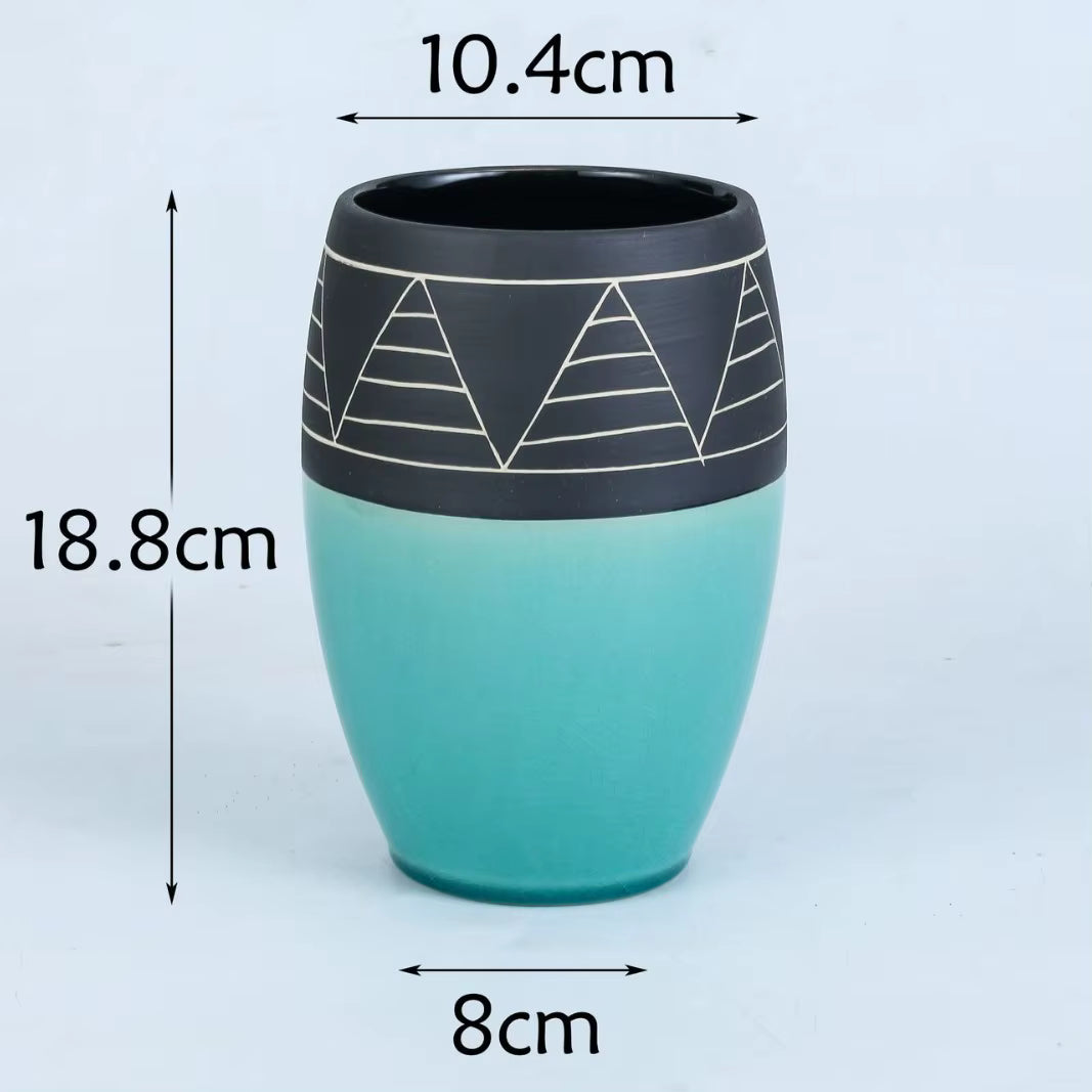 Teal and black ceramic cup with geometric design, shown with measurements on a white background.