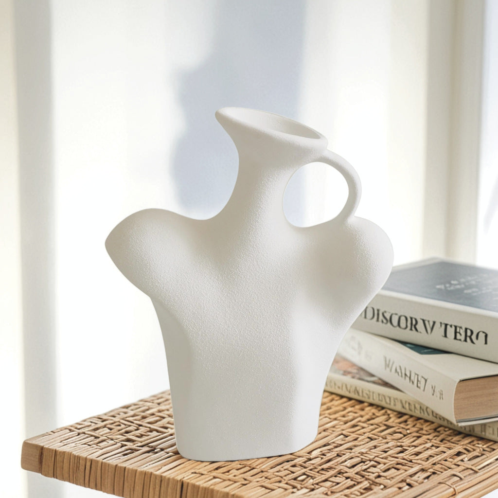 White abstract vase on a wooden surface with books in the background