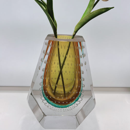 Decorative glass vase with a plant on a white background