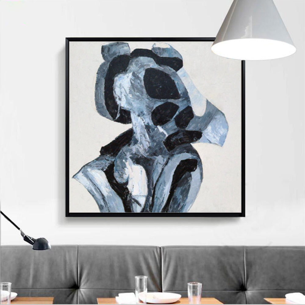 Abstract art piece in a black frame on a wall above a gray sofa.