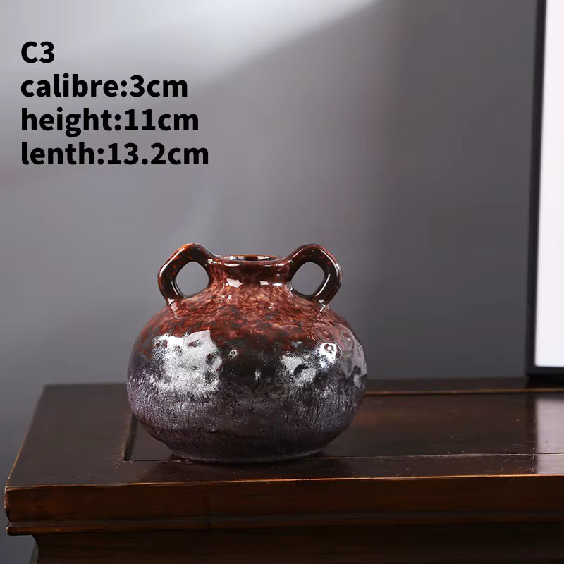 Small ceramic vase with two handles on a wooden surface against a gray background