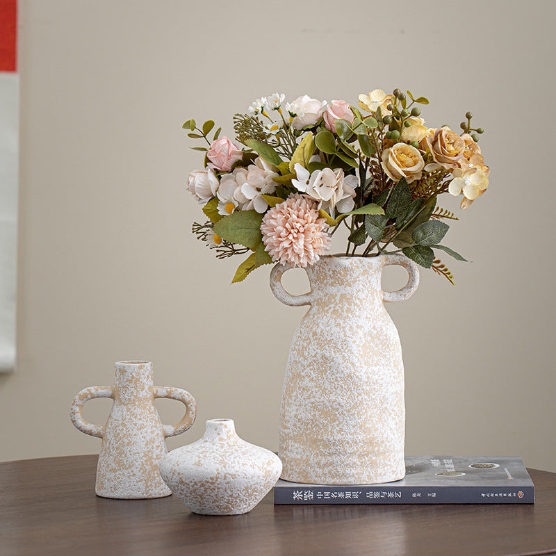 Set of three decorative vases with a floral arrangement on a table.