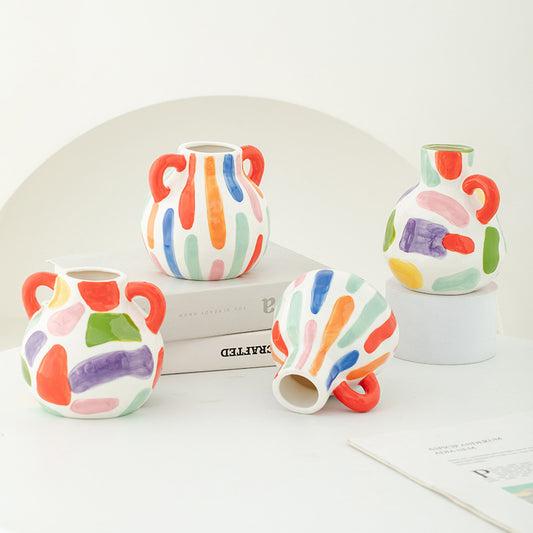 Set of colorful ceramic vases on a white surface with a magazine underneath.
