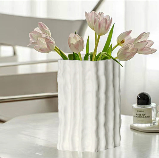 White vase with pink tulips on a table with a blurred background