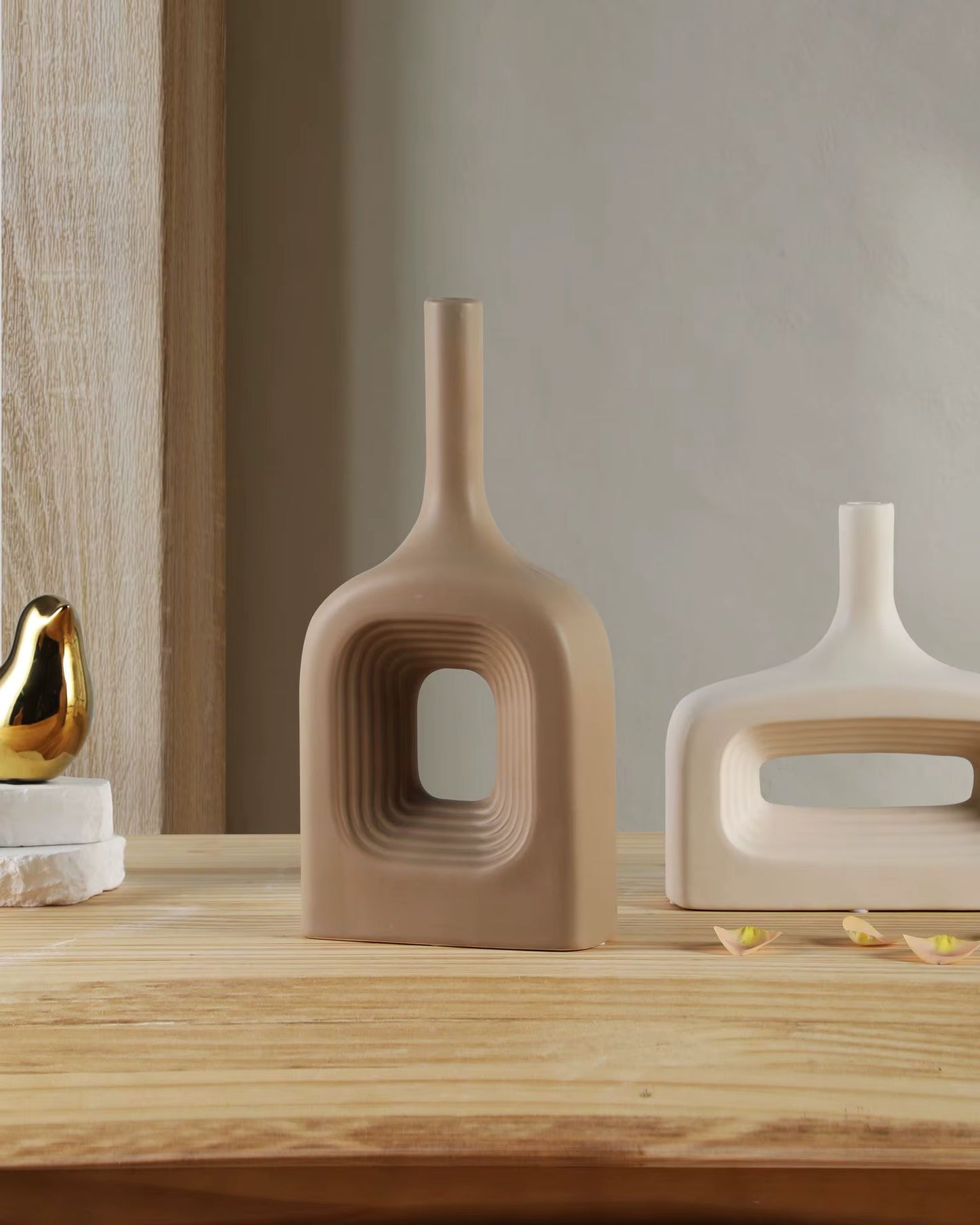 Three modern ceramic vases on a wooden surface with a neutral background