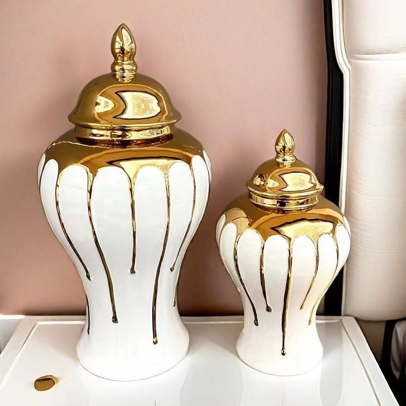 Two decorative jars with gold lids on a white surface against a pink background