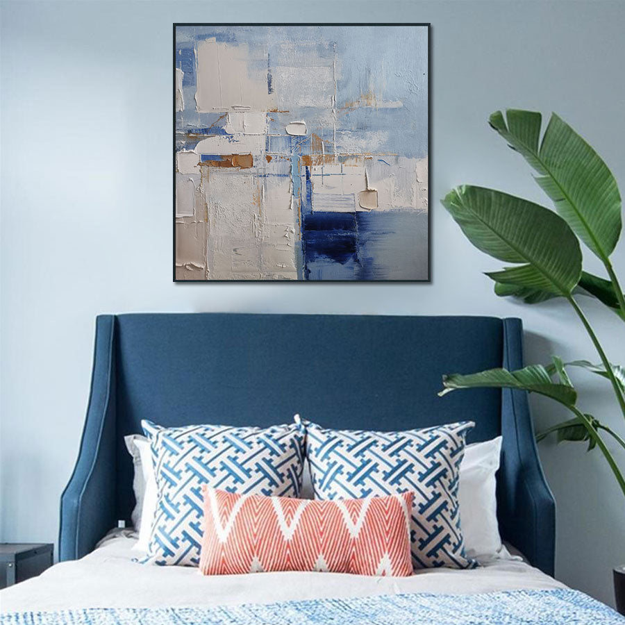 Bedroom with blue upholstered headboard, patterned pillows, and abstract art on wall.