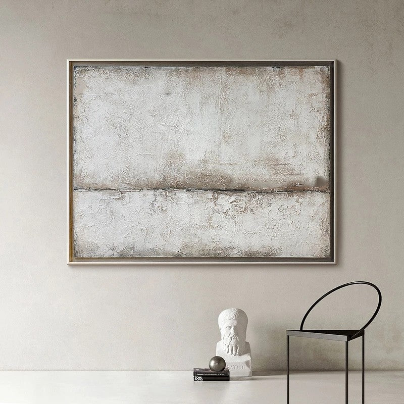 Abstract art piece in a neutral-toned frame on a wall with decorative items below.