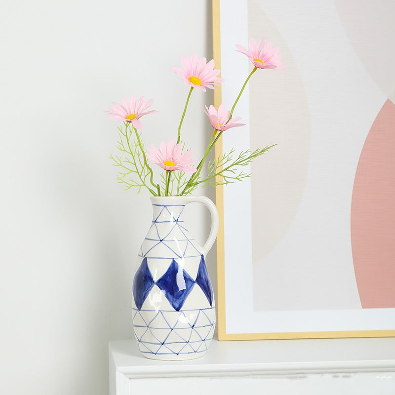 Decorative vase with pink flowers on a shelf next to a framed picture