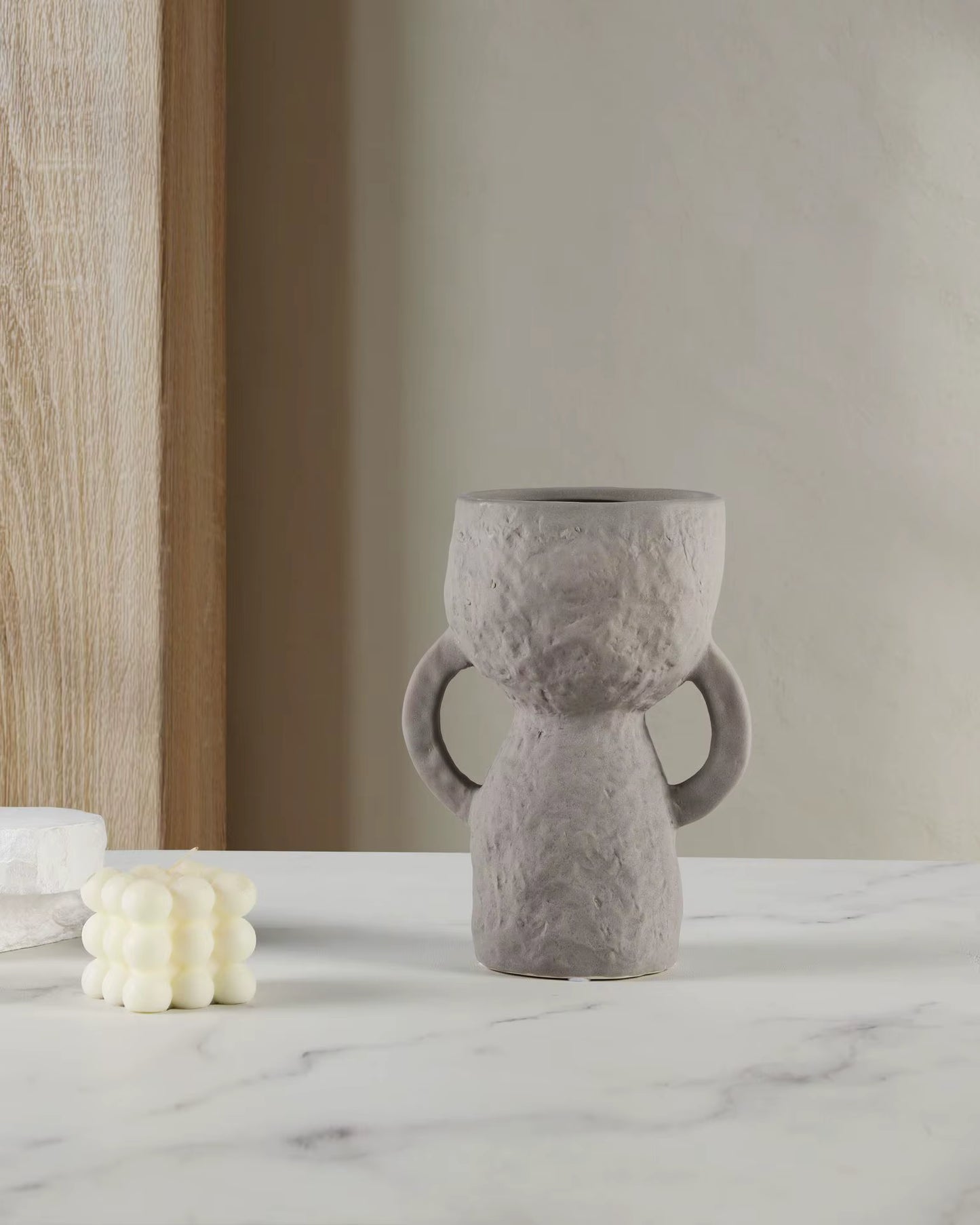 Gray textured vase on a marble surface with a neutral background