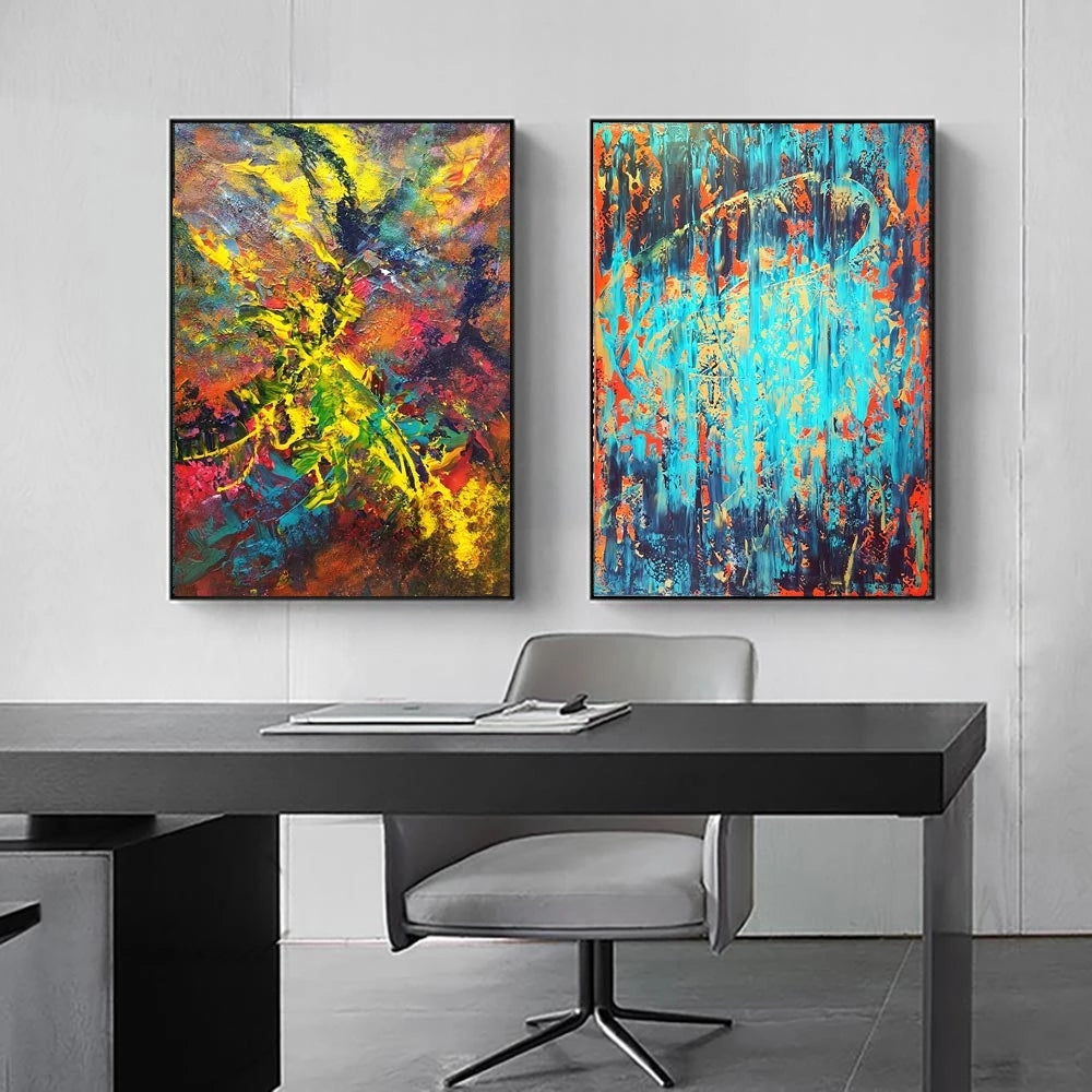 Two abstract paintings on a wall above a desk with a chair.