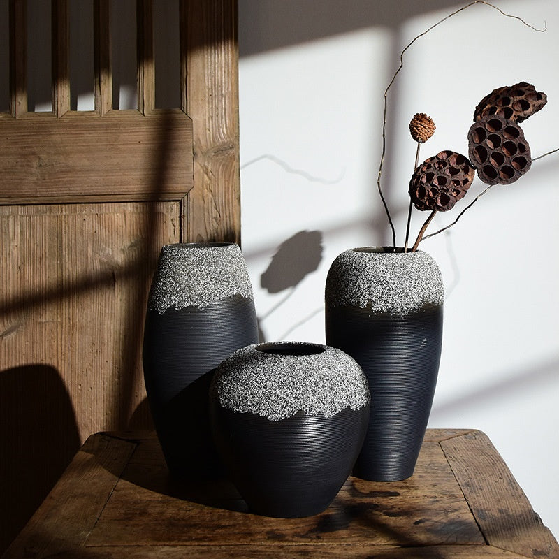 Two black textured vases with white accents on a wooden surface.