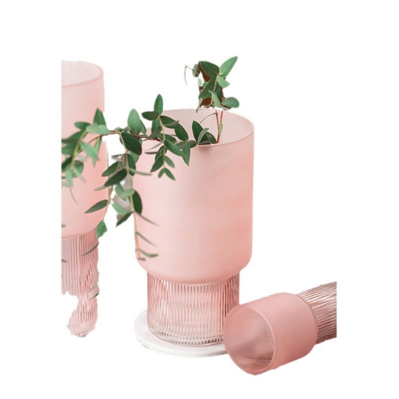 Pink ribbed vase with green leaves on a white background