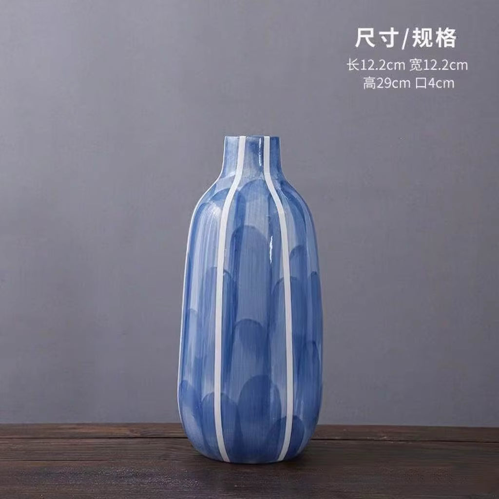 Blue and white striped vase on a wooden surface with a gray background