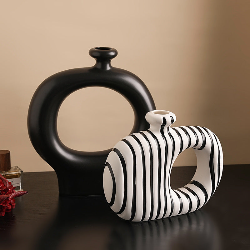 Black and white decorative vases on a reflective surface with a beige background