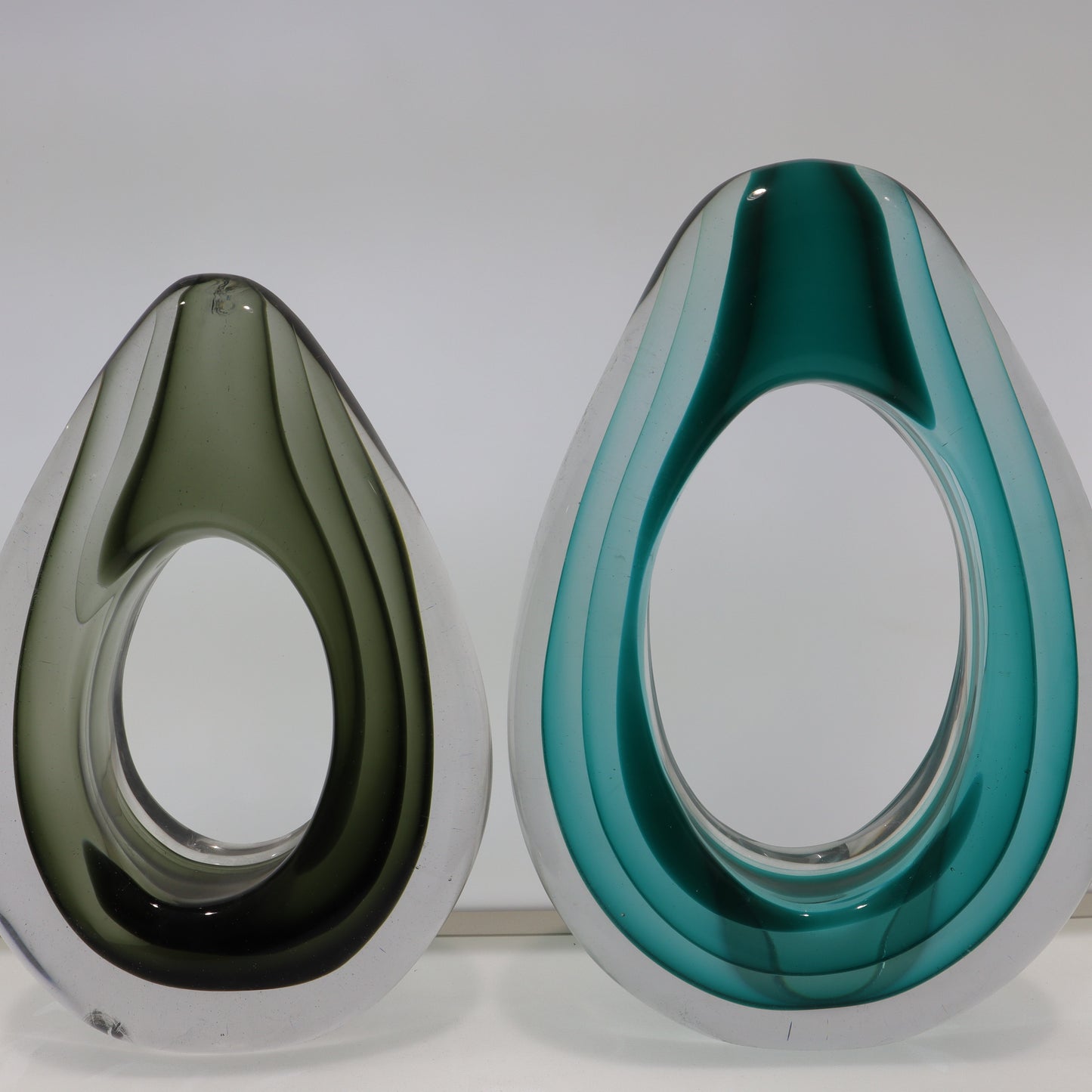 Two teardrop-shaped objects, one green and one blue, on a white background
