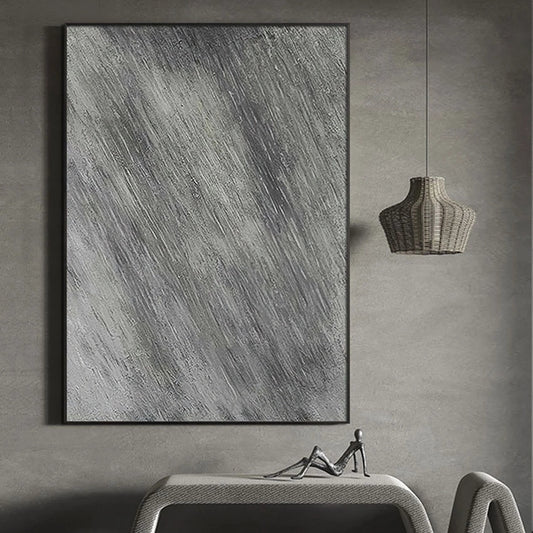 Abstract art piece on a gray wall with a table and lamp below.