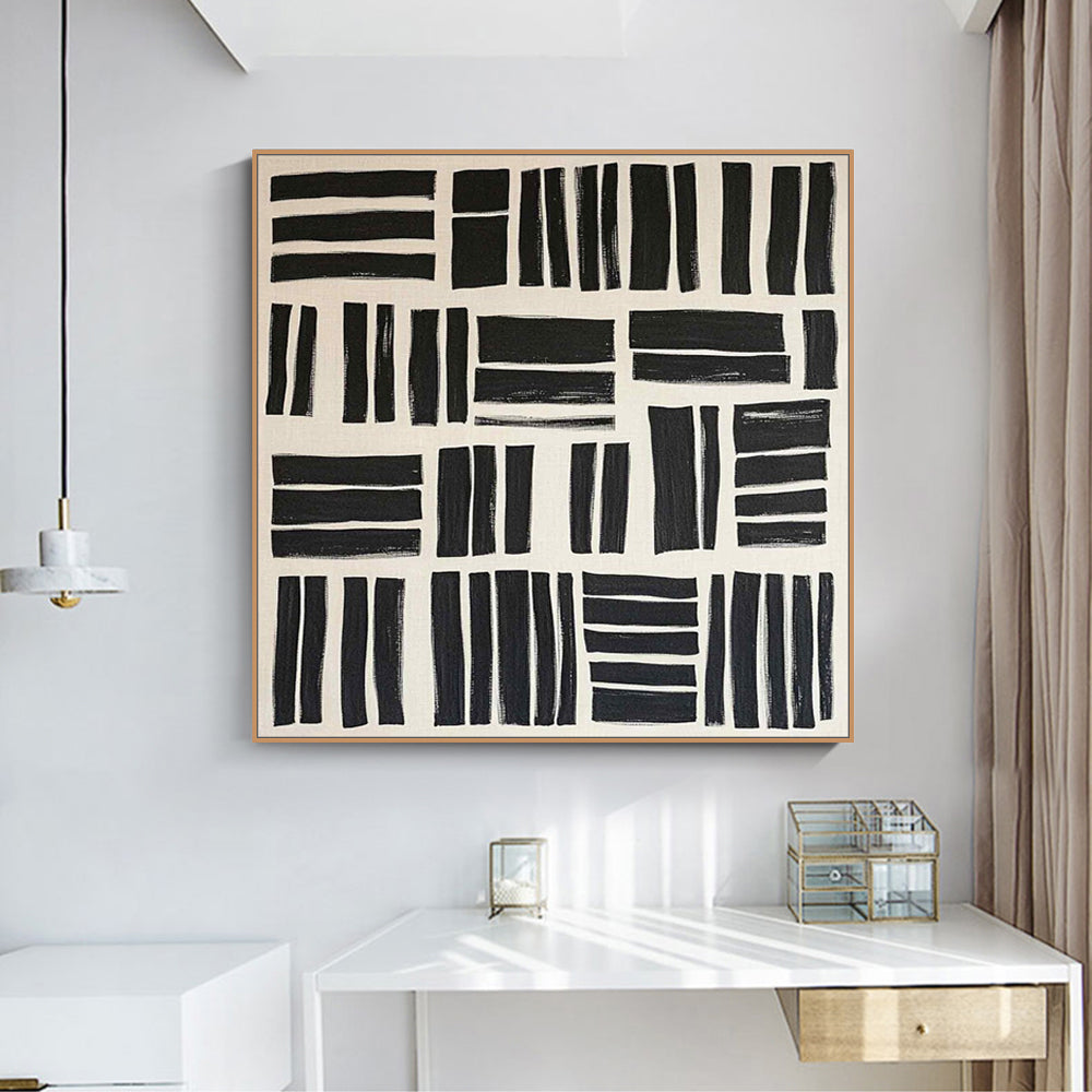 Abstract black and white artwork on a wall above a white desk.