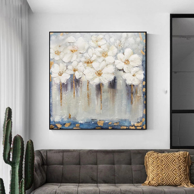 Floral painting on a wall above a sofa with a cactus plant and decorative pillow.