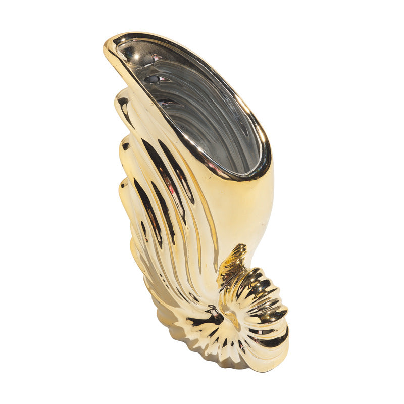 Gold-colored object with a shell design on a white background