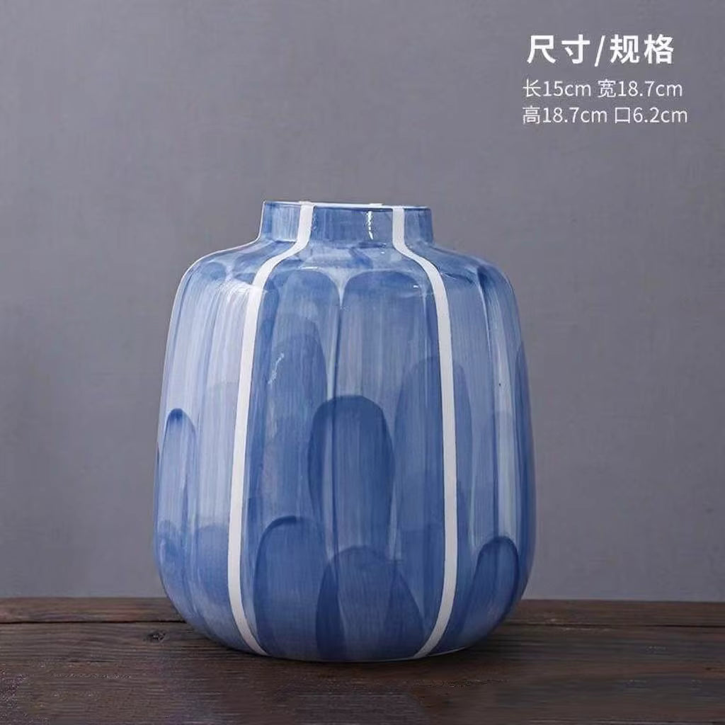 Blue and white striped vase on a wooden surface with a gray background