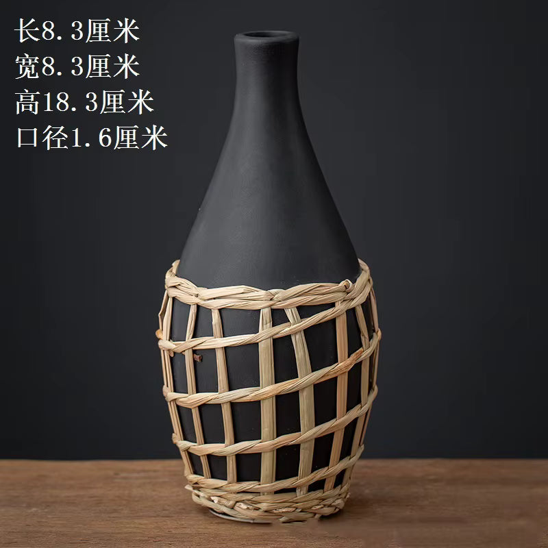 Black vase with woven basket design on a wooden surface and dark background