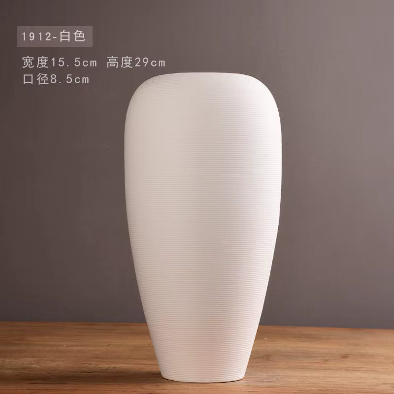 White ceramic vase on a wooden surface with a gray background