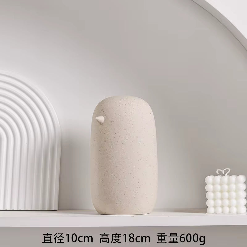 Beige ceramic vase on a white shelf with a minimalistic background