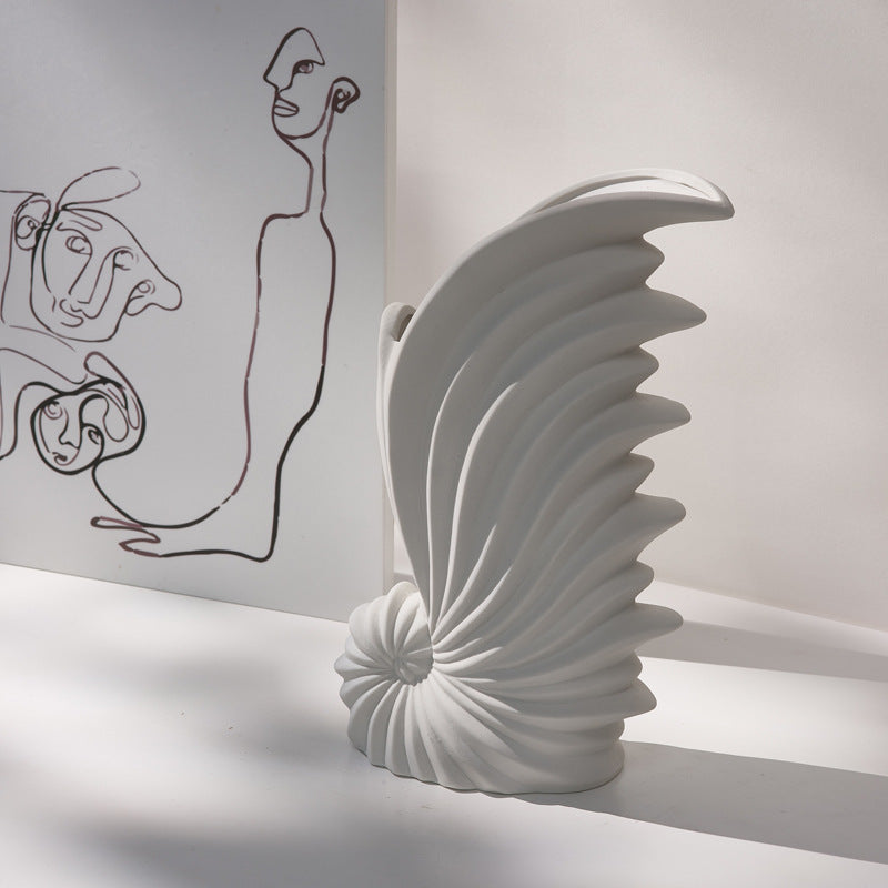 White abstract sculpture on a gray surface with a minimalistic drawing in the background