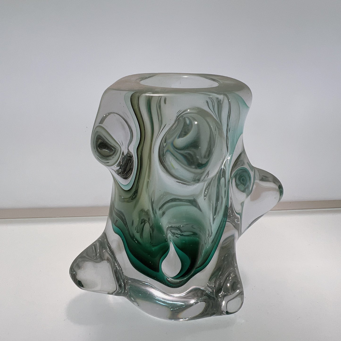 Glass candle holder with green and clear swirl design on a white background