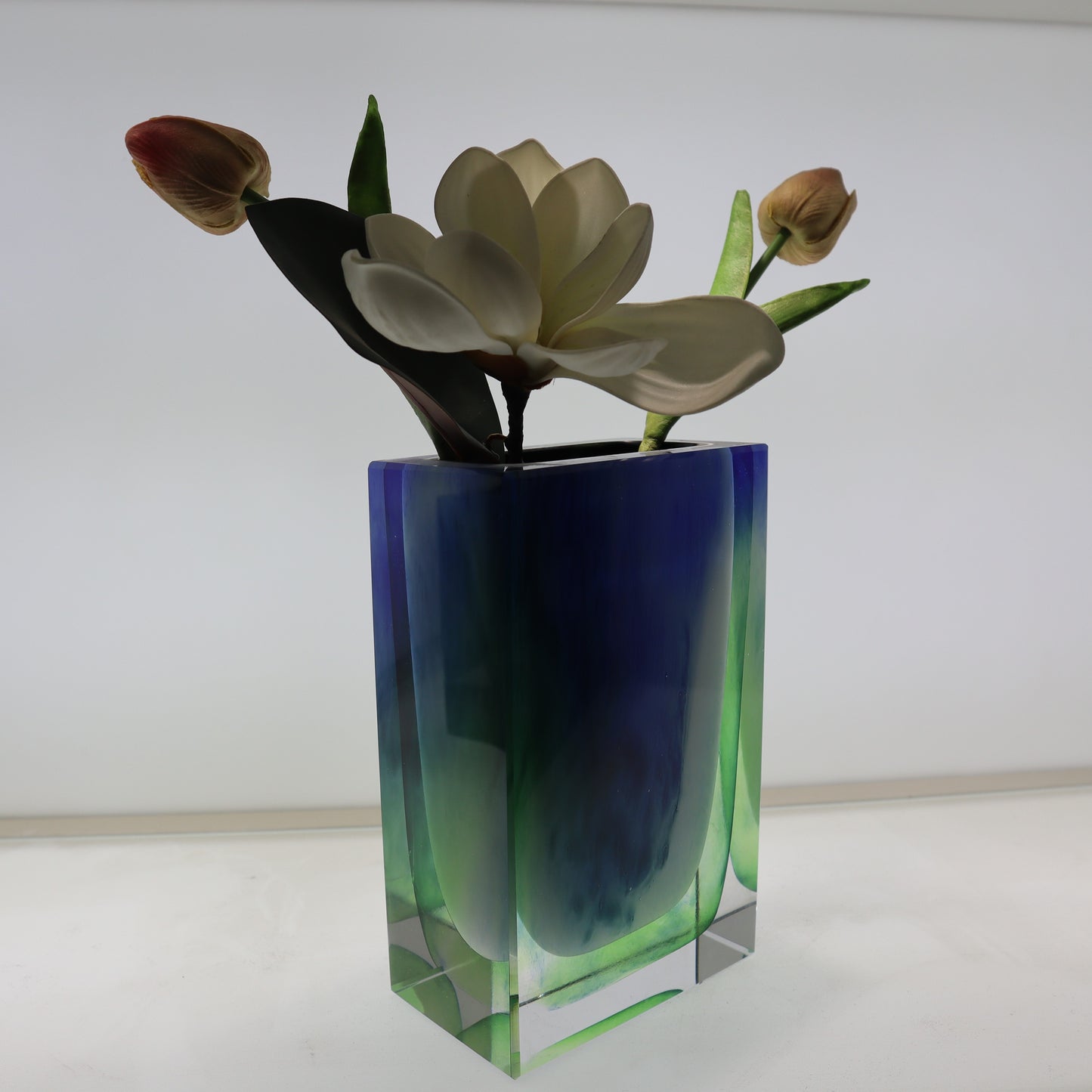 Colorful glass vase with flowers on a white background