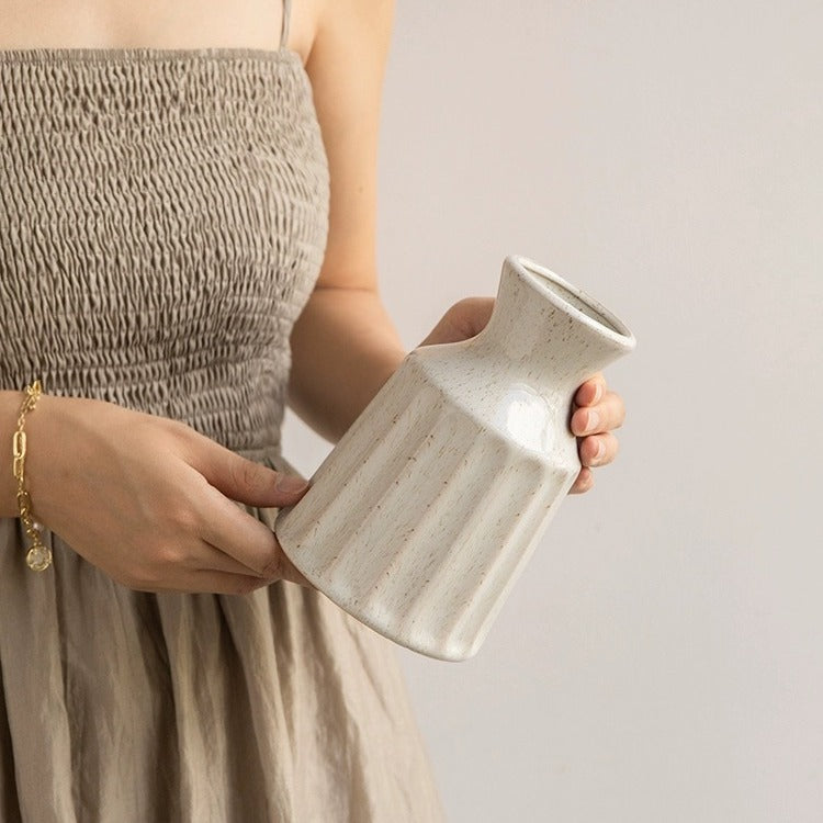 Person holding a ceramic vase against a plain background