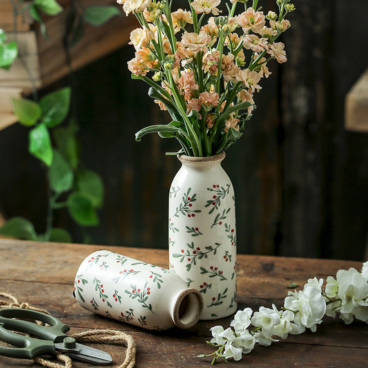 Decorative vase with floral design on a wooden surface with flowers and scissors.
