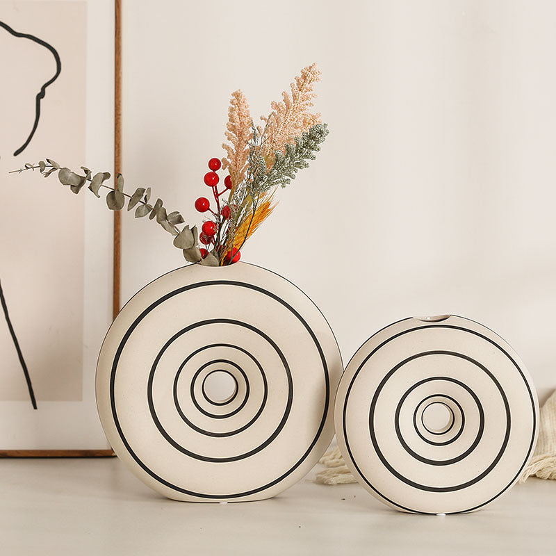Two decorative vases with circular patterns on a light surface.